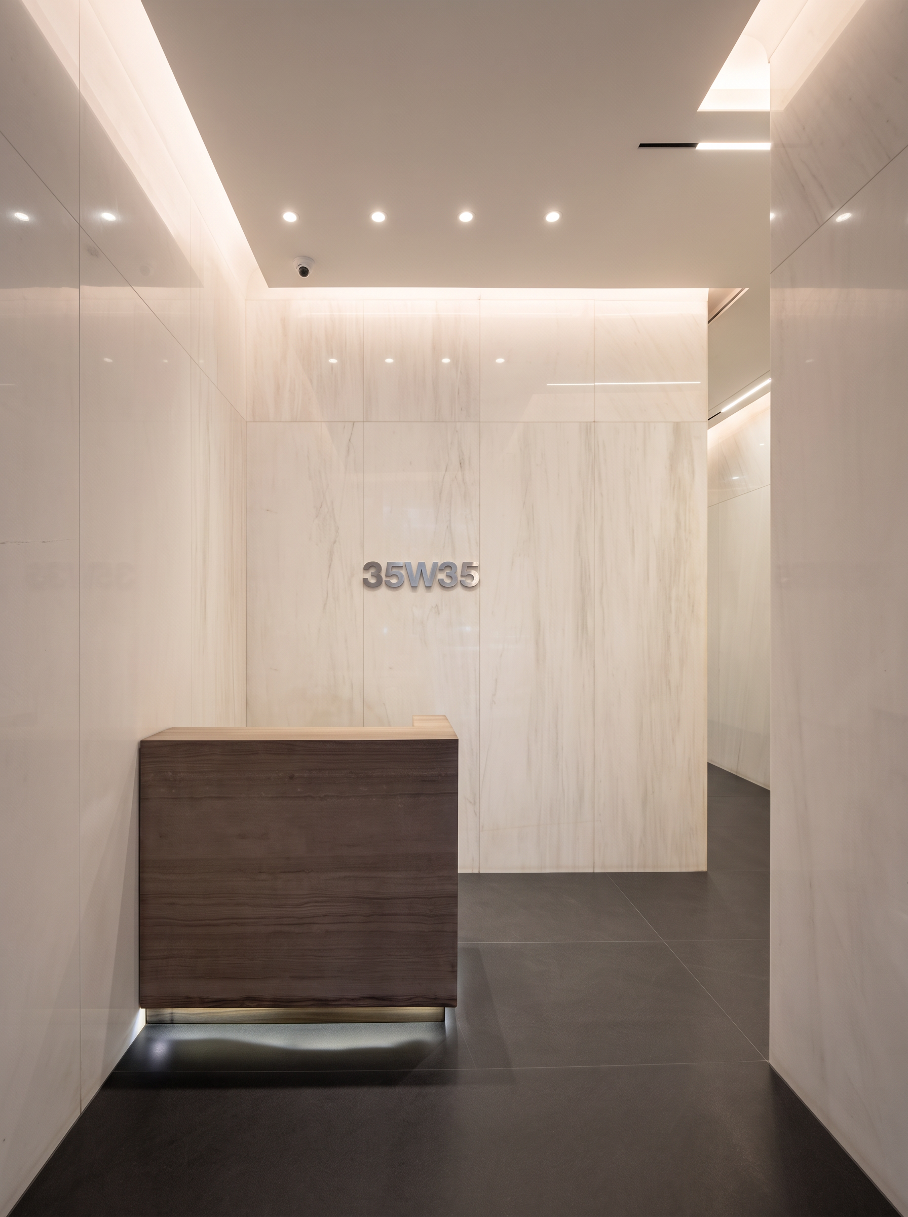Modern white marble lobby at 35W35 with dark stone floor and backlit reception desk